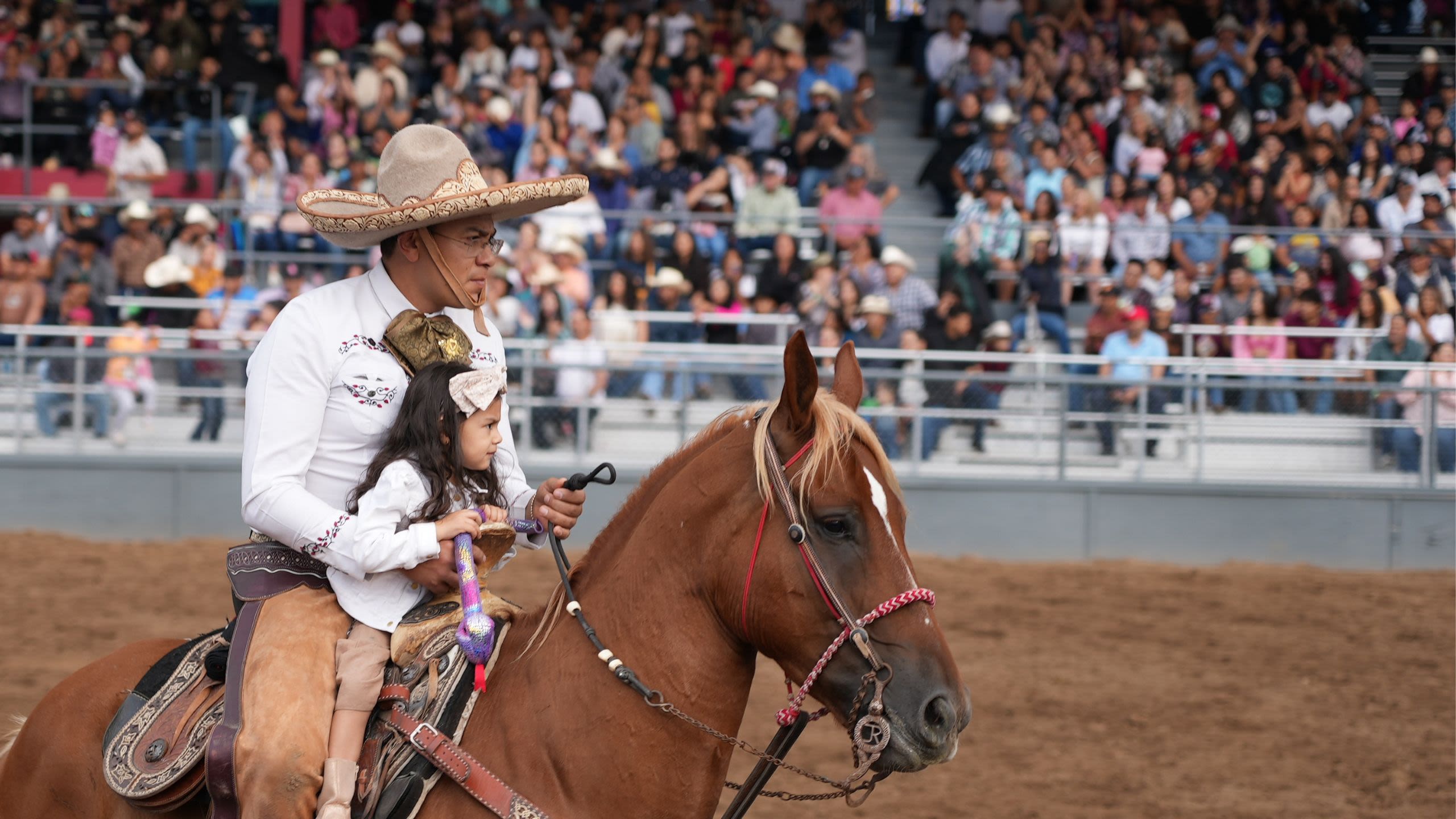 A man and a little girl riding horseback during the Charreada event of the Adams County Fair.
