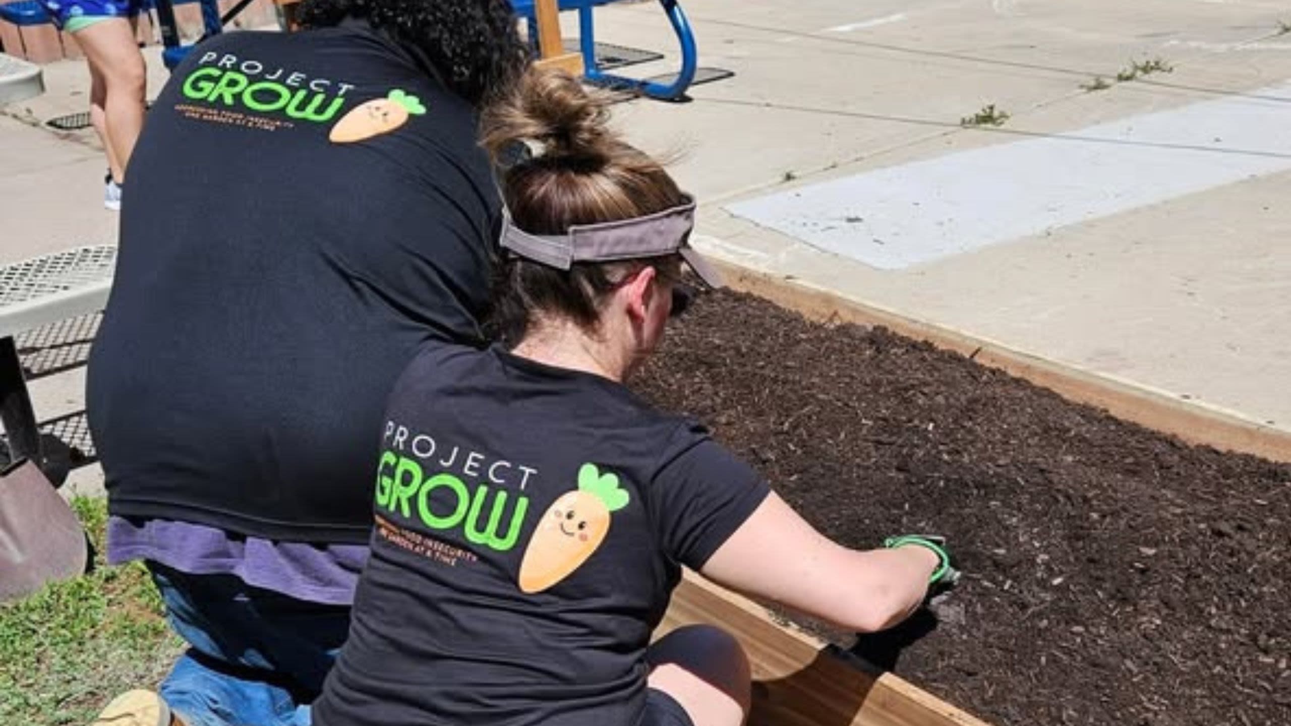 Two people plant seeds in the ground as part of Project Grow.