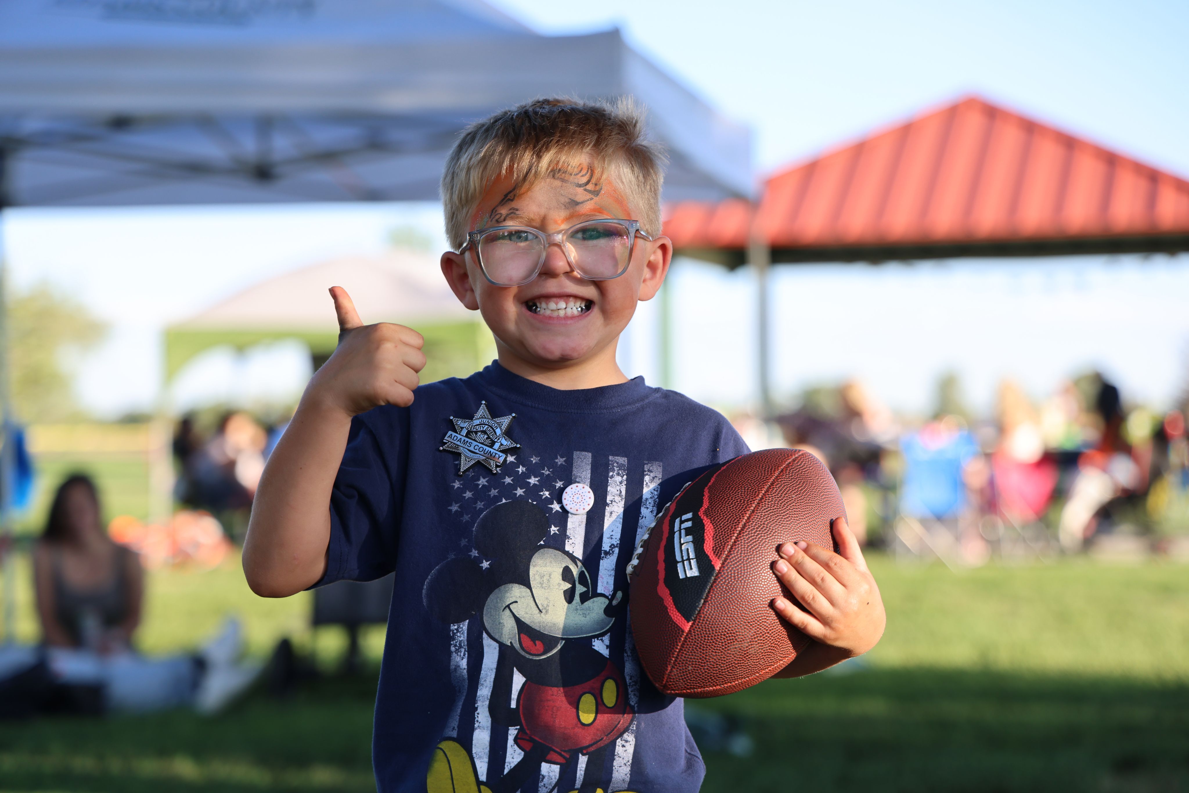 A little boy flashing a thumbs up at Stars & Stripes.
